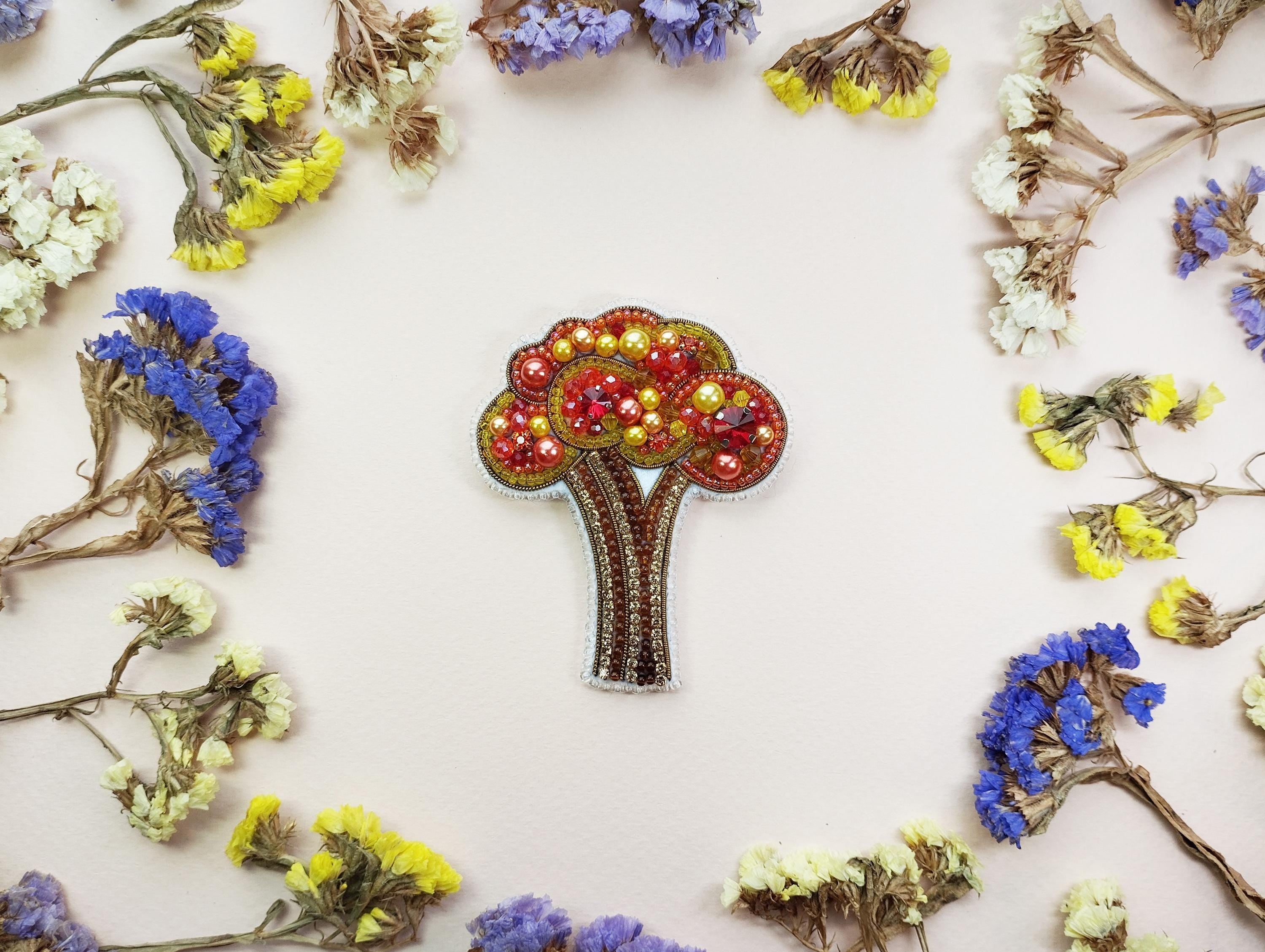 a brooch with a tree on it surrounded by flowers